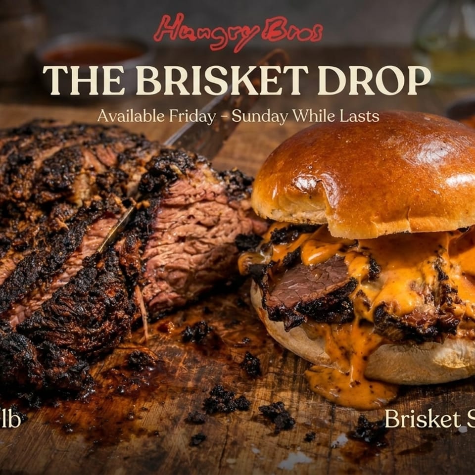 A large, smoked brisket is sliced on a wooden board next to a brisket sandwich with melted cheese.